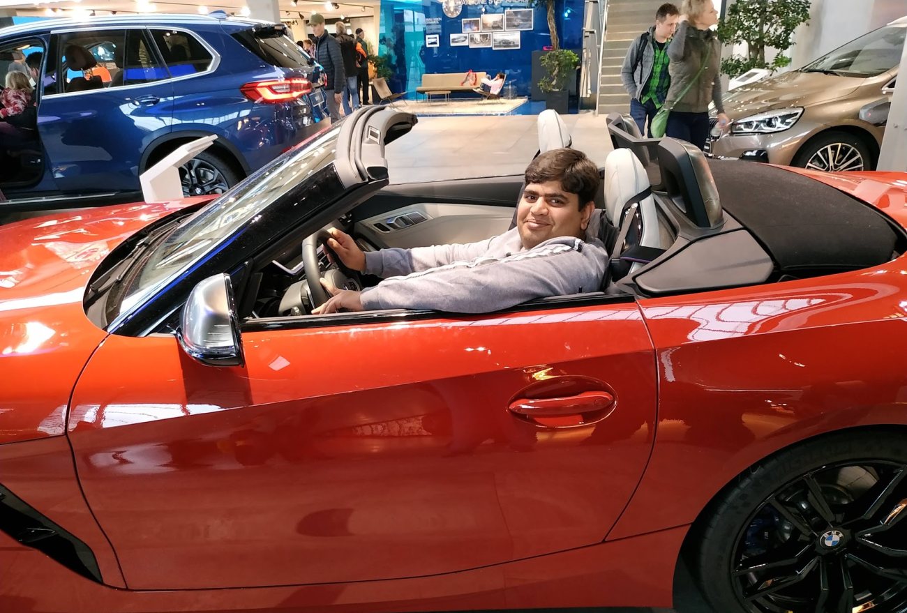 Vishwa Ranjan seated in a red BMW Z4 roadster