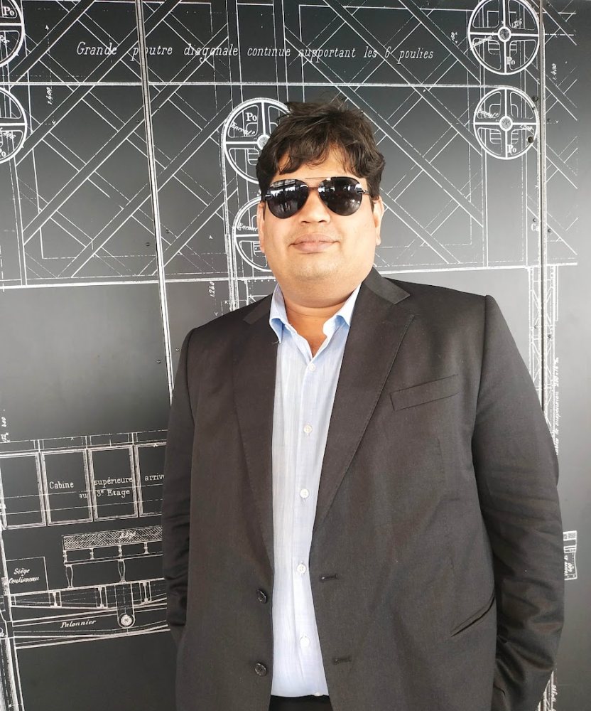 Vishwa Ranjan beside displays of the Eiffel Tower's original engineering drawings